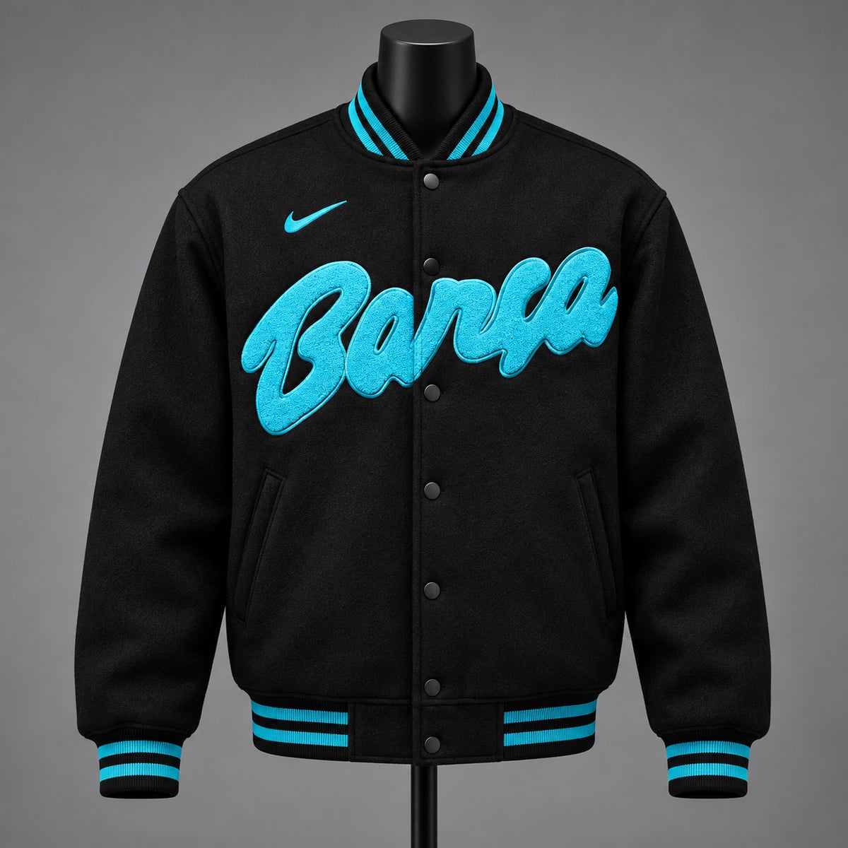 Black and turquoise FC Barcelona Barça varsity jacket on mannequin showing turquoise script lettering, swoosh and snap front